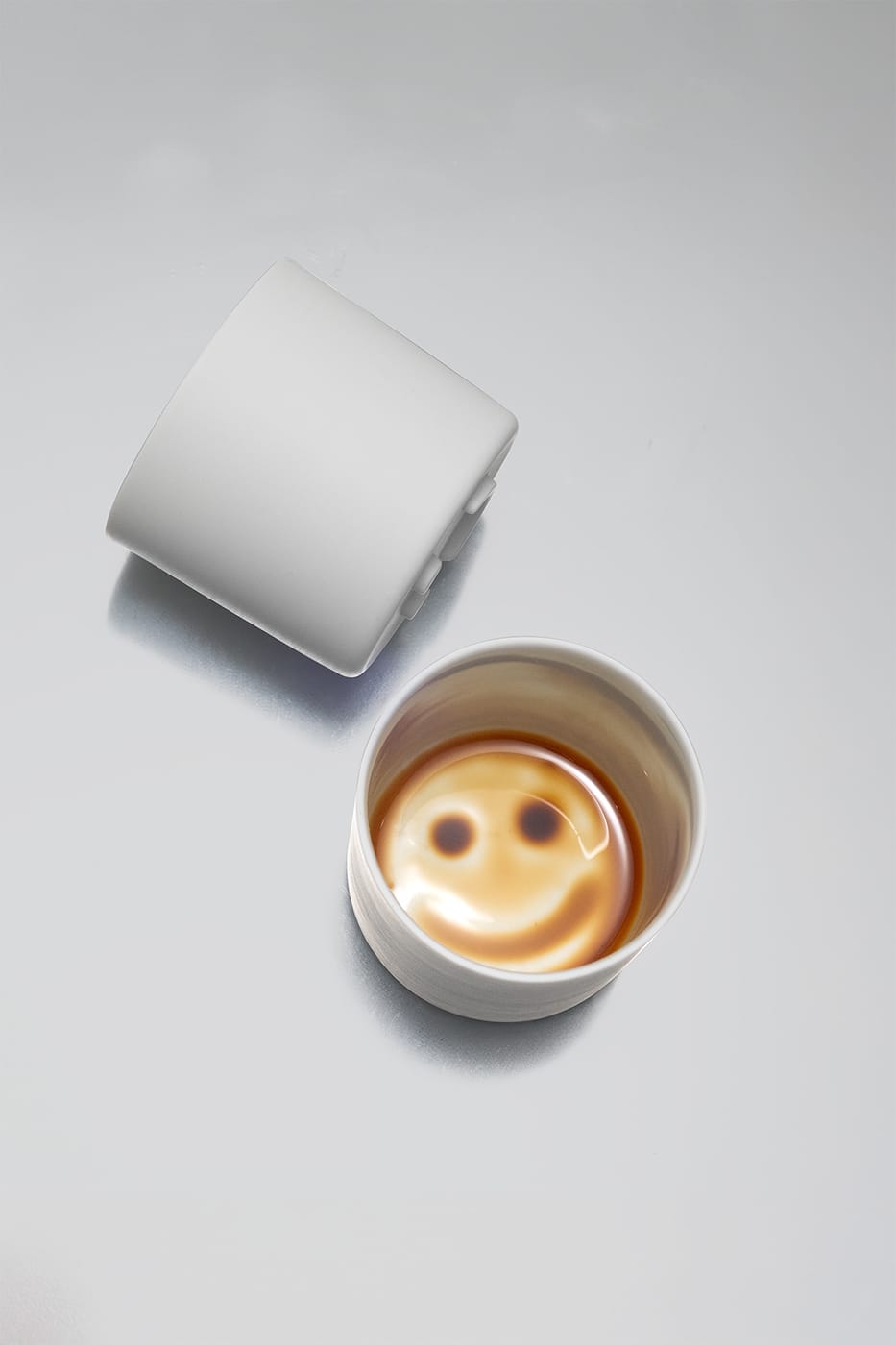 Two Smileycups — one showing a smile at the bottom of the finished coffee